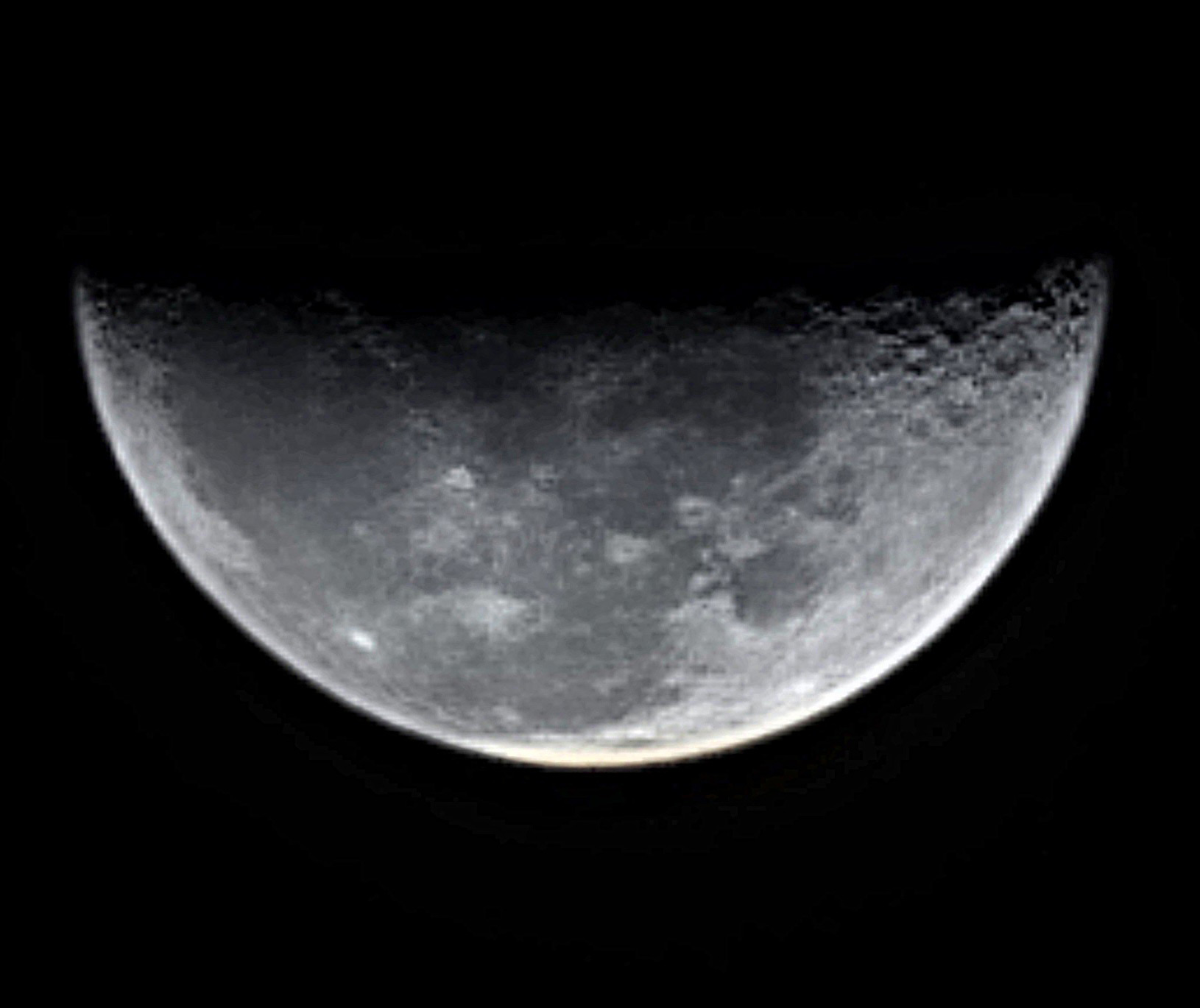 Scenic shot of the half moon hanging in the pitch black night sky with the contrast on the light and dark sides of the moon